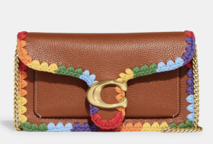 A brown bag from the COACH Pride collection with a rainbow chain on it.